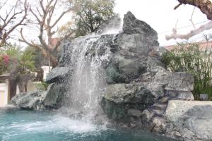 a waterfall in a pool in a yard at Lux Hotel in Luang Prabang