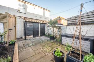 a backyard with a courtyard with plants and a garage at Pink Cottage, Leiston in Leiston
