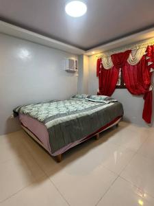 a bedroom with a bed in a room with red curtains at Koenigs Lodging House in Bocaue