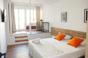 a bedroom with a bed with orange pillows and a window at Hamilton Suites in Barcelona