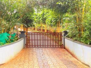 a gate with a brick walkway in front of trees at ARAMAM SERVICE VIlla in Mananthavady