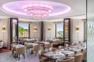 a restaurant with tables and chairs and a large pink chandelier at Hilton Budapest in Budapest