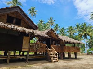 a hut with a staircase and palm trees at Palawan Ecolodge in Malabuñgan