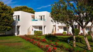 a white house with red flowers in a yard at Globales Lord Nelson - Only adults in Santo Tomás