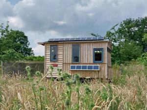 a tiny house with solar panels on top of a field at EcoPod Holidays in Alton