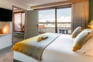 a bedroom with a bed with a view of snow covered mountains at La Cachette, Friendly Hotel & Spa in Arc 1600