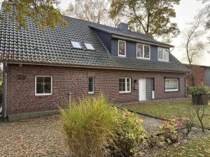 a red brick house with a black roof at Ferienwohnung Meyer in Neuenkirchen