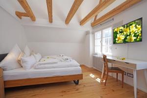 a bedroom with a bed and a desk and a television at Villa Primavera in Nesselwang