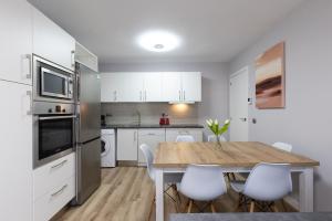 a kitchen with a wooden table and white cabinets at FORMENTOR Apartment in Salou
