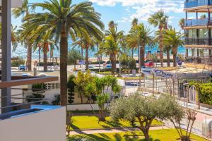 a view of the beach and palm trees from a building at FORMENTOR Apartment in Salou