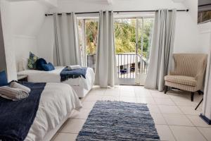 a bedroom with two beds and a chair and a balcony at St Andrews exclusive guesthouse in Klerksdorp