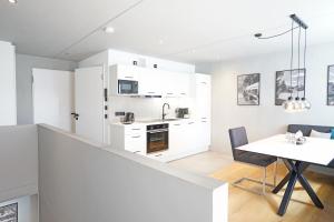 a kitchen with white cabinets and a dining table at Exclusive Maisonettewohnung! in Nesselwang