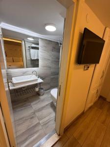 ein Badezimmer mit Toilette, Waschbecken und Fernseher in der Unterkunft The Constantine Hotel in Istanbul