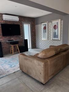 a large brown couch in a living room with a flat screen tv at Villa Bella in George