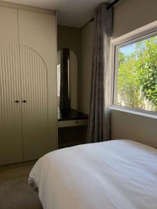 a bedroom with a white bed and a window at Villa Bella in George