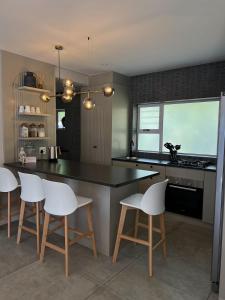a kitchen with a black counter and white chairs at Villa Bella in George +8 photos