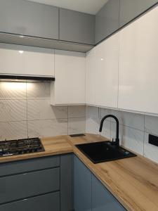 a kitchen with white cabinets and a sink and a stove at Apartament SIEDEMNAŚCIE in Sanok