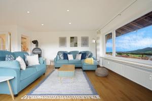 a living room with blue couches and a large window at Panoramaweg in Wertach