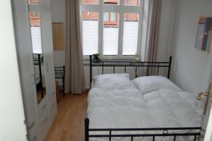 a bed with white sheets in a room with windows at Ferienhaus Wismar in Wismar