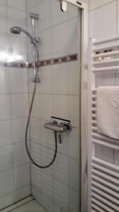 a shower with a hose in a white tiled bathroom at Ferienhaus Wismar in Wismar