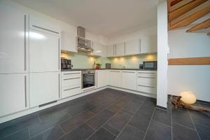 a kitchen with white cabinets and a tile floor at Chalet am Breitenberg Apt1 in Pfronten