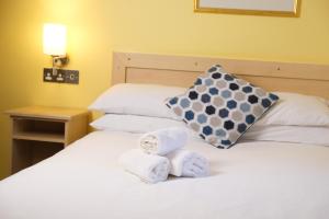 Zwei Handtücher liegen mit einem Kissen auf einem Bett. in der Unterkunft Feerick's Hotel in Rathowen