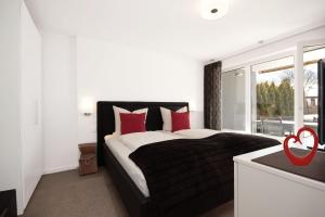 a bedroom with a bed with red pillows and a window at N-Appartement Falkenstein in Nesselwang