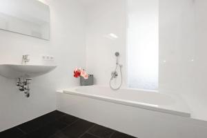 a white bathroom with a sink and a bath tub at N-Appartement Falkenstein in Nesselwang +6 photos