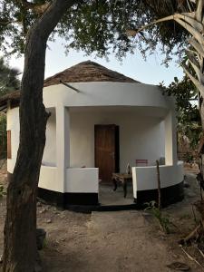 a small white building with a door and a tree at Tida-Ecolodge in Kartung