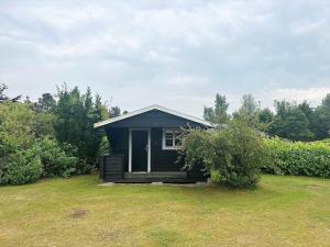 a small black house in a grassy field at M252-Vaeggerlose-Bjergfruevej-6 in Bøtø By