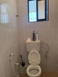 a bathroom with a white toilet with a window at JnG HOMES in Malindi +1 photo