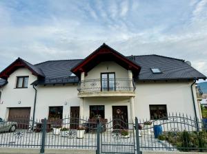 a large white house with a black roof at Willa u Marioli in Ściegny