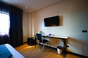 a hotel room with a desk and a tv on the wall at PROXY Plus Pangasinan in Alaminos