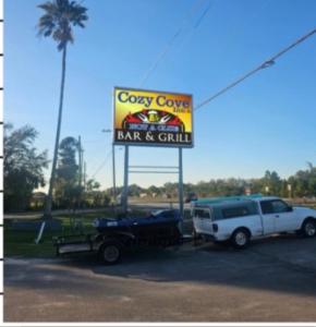 a white truck parked in front of a bar and grill sign at Cozy Cove inn in Saint Cloud