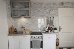 a white kitchen with a stove and a sink at Iva Penthouse in Novi Sad