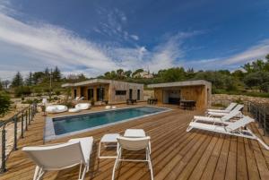 a deck with a pool and chairs and a house at La Possibilité d'une Ile in Apt