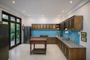 a kitchen with wooden cabinets and blue tiles at HELLO VILLA & SPA in Hue