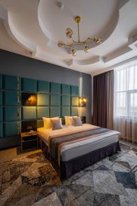 a bedroom with a large bed with a blue wall at Monotel Hotel in Ustʼ-Kamenogorsk