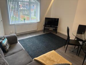 a living room with a couch and a tv and a table at Three bed house in Wolverhampton in Bushbury