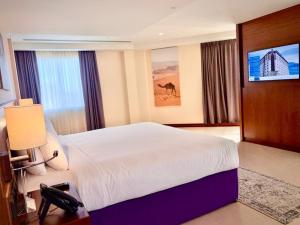 a hotel room with a bed and a flat screen tv at Kyriad Hotel Salalah in Salalah