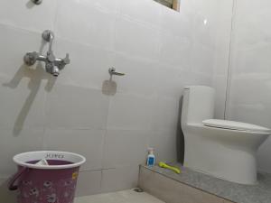 a white bathroom with a toilet and a bucket at BiJOY VILLA in Guwahati