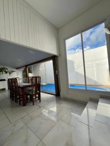 a dining room with a table and chairs and windows at Casa com Piscina em Xangri-Lá RS in Xangri-lá