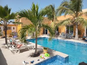 a swimming pool with palm trees and lounge chairs at Hôtel Colibri Lac Rose in Niaga