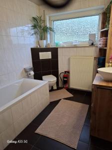 a bathroom with a tub and a toilet and a sink at Ferienwohnung Seeblick in Langweiler