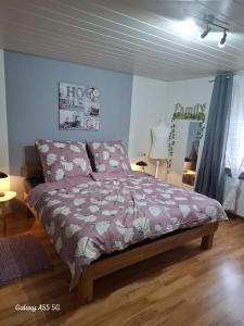 a bedroom with a bed with a purple comforter at Ferienwohnung Seeblick in Langweiler