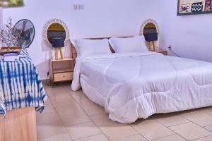 ein Schlafzimmer mit einem weißen Bett und zwei Lampen in der Unterkunft Villa Masada in Grand-Bassam
