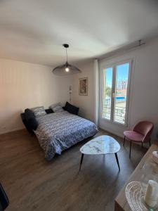 a bedroom with a bed and a table and a window at Elégance du Golfe in Vallauris