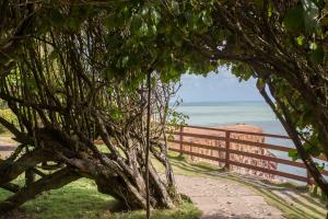 a wooden fence next to the ocean with a tree at Hotel Ponta do Madeiro in Pipa