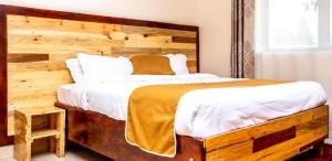 a bedroom with a large bed with a wooden headboard at Latitudo Suites Uganda in Kajansi