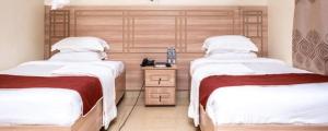 a bedroom with two beds and a wooden headboard at Latitudo Suites Uganda in Kajansi